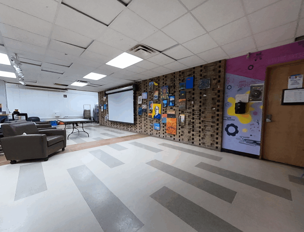 The interior of Living ArtsEngine's Creative Suite with painted wall, projector screen, and cushioned chair