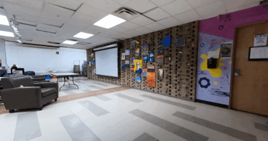 The interior of Living ArtsEngine's Creative Suite with painted wall, projector screen, and cushioned chair